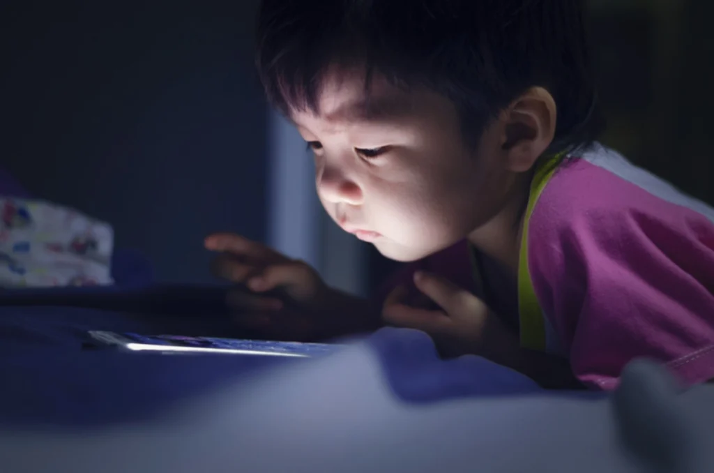 A young child interacting with a tablet, symbolizing the influence of social media exposure on early childhood development.