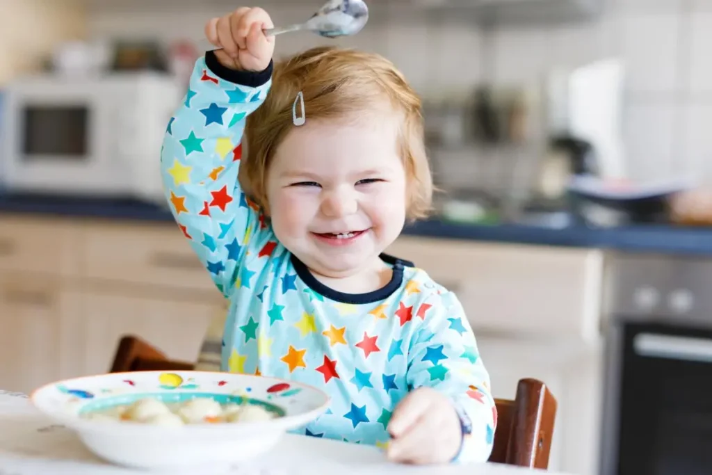 A toddler enjoying a colorful and nutritious meal with playful food arrangements.